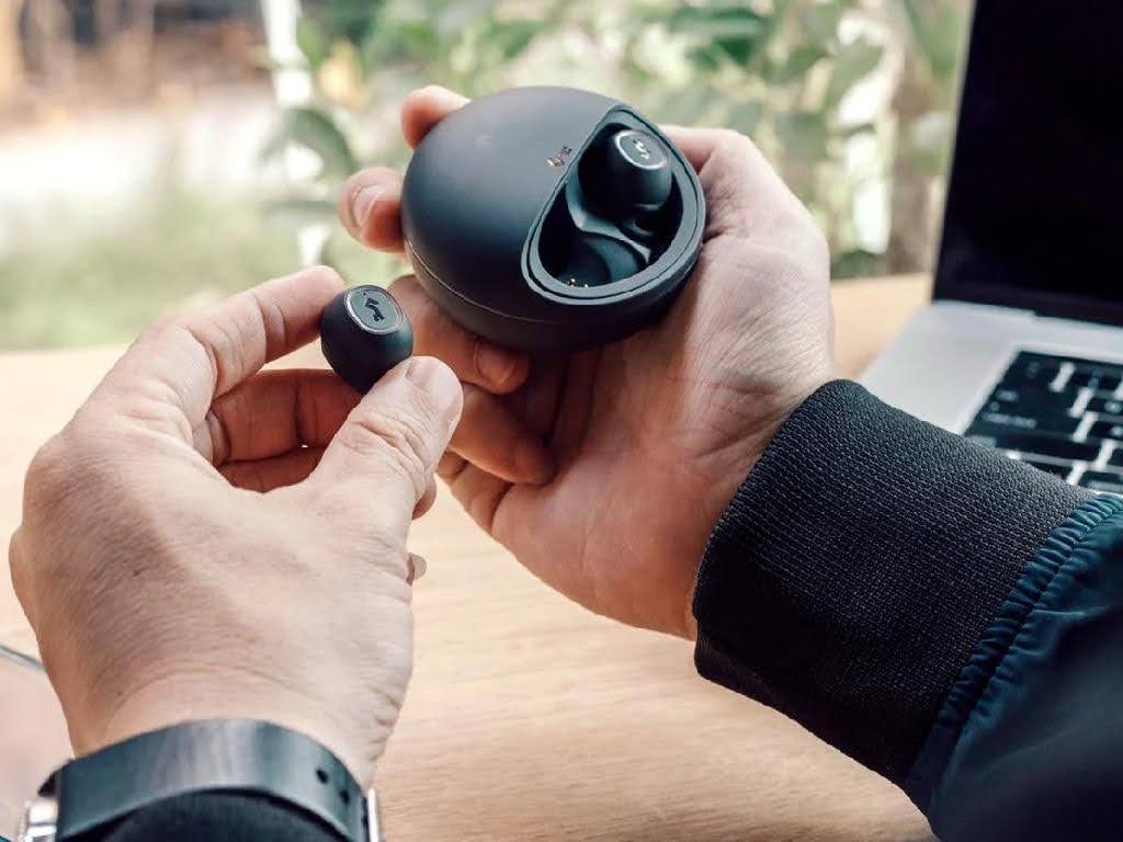 فردی در حال خارج کردن هندزفری بلوتوث QCY از کیس شارژ